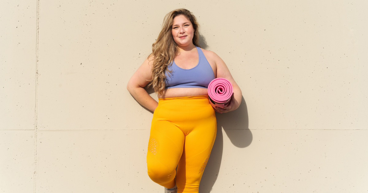 a curvy woman with a yoga mat in her hands